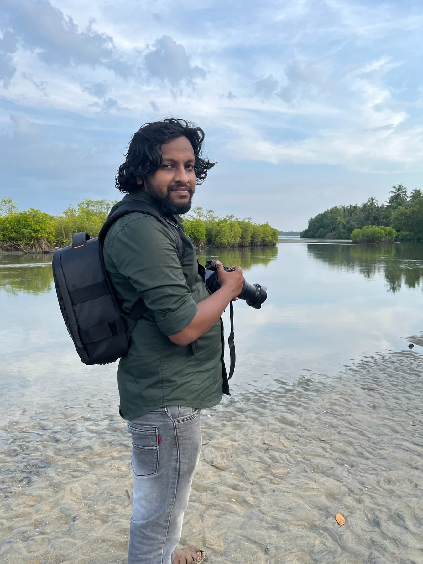 Akash with his camera beside a quiet waterway
